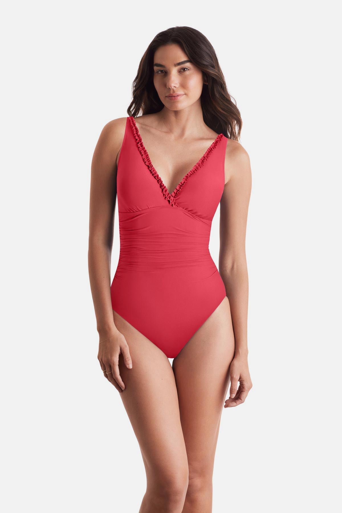 Woman wearing a coral-colored one-piece swimsuit with frills on the edges