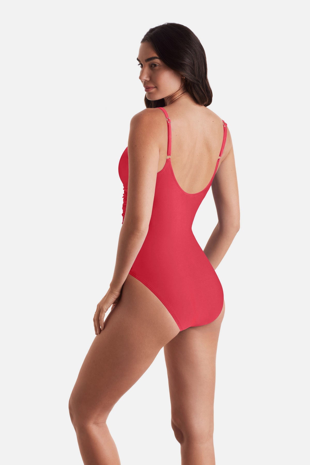 Woman turned left wearing a coral-colored one-piece swimsuit with frills on the edges