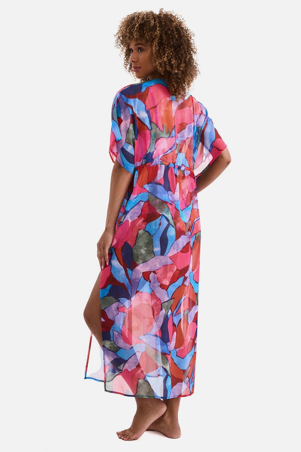Woman turned left wearing a multicolored abstract printed sheer swim cover up