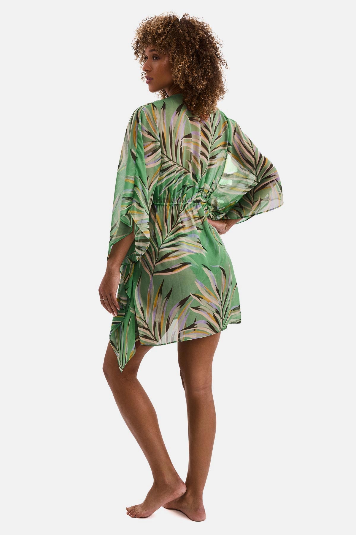 Woman turned left wearing a multicolored leaf print sheer swim cover up