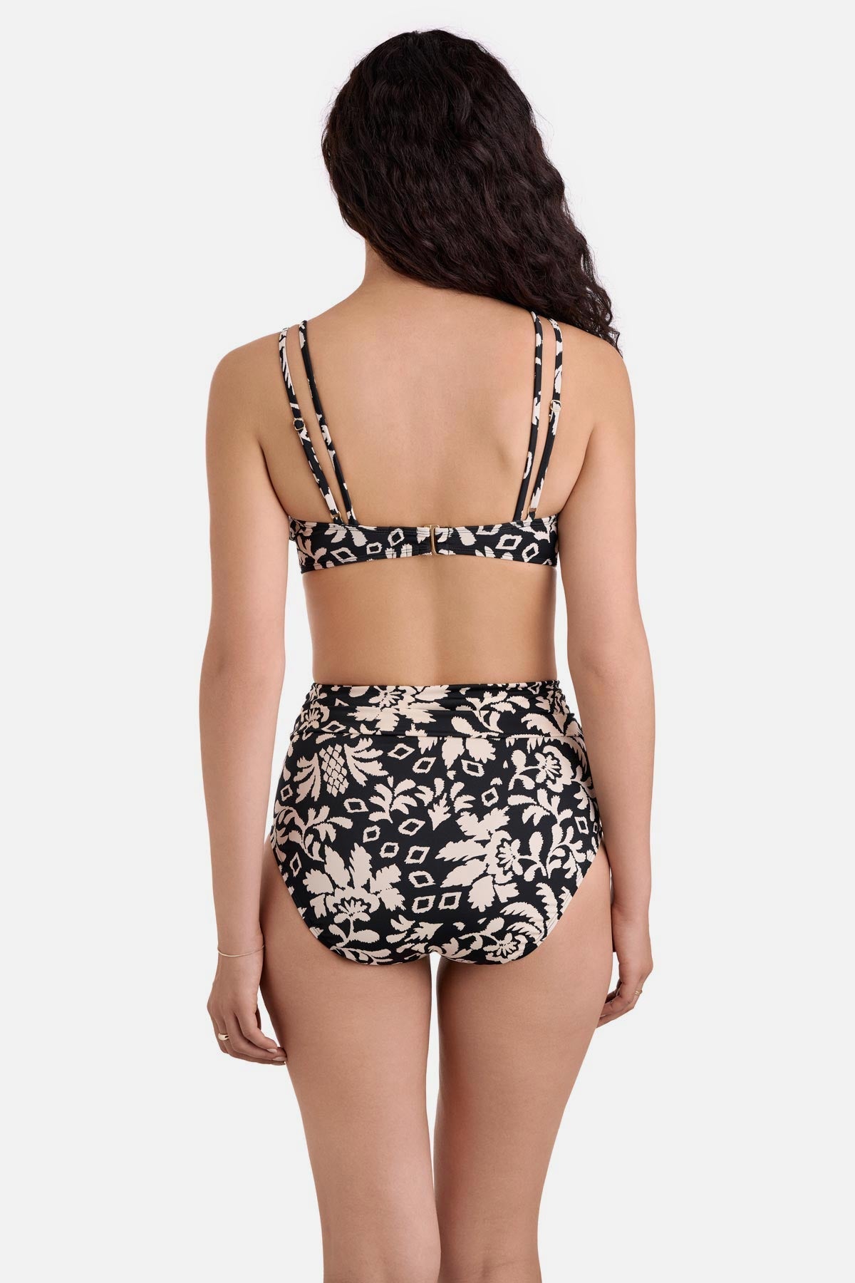 Woman turned away wearing a black and white palm tree printed bikini top with high waisted matching swim bottoms