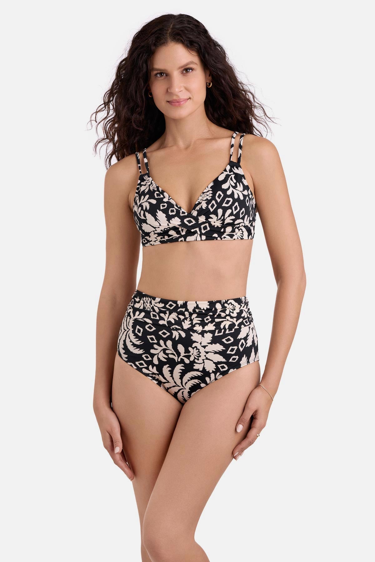 Woman wearing a black and white palm tree printed bikini top with high waisted matching swim bottoms