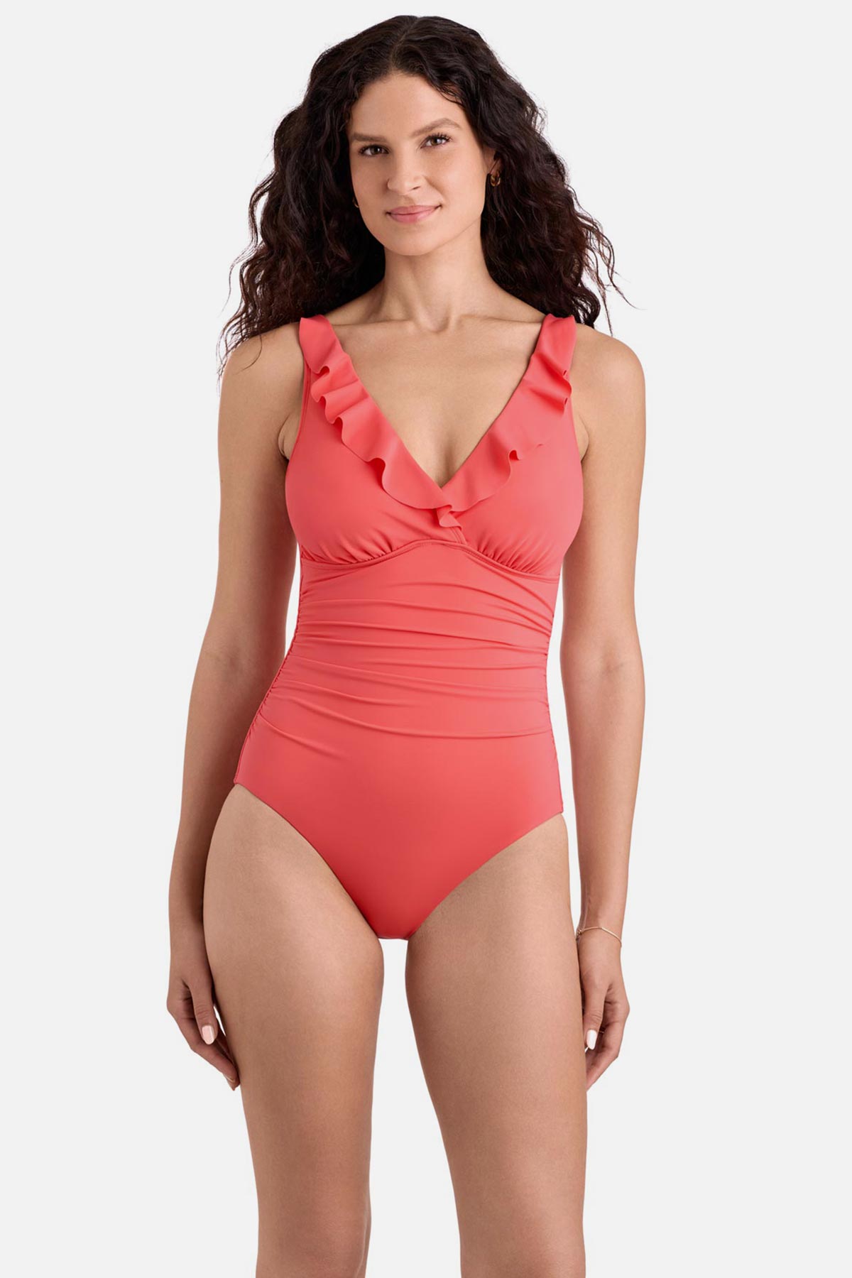 Woman wearing a coral pink one-piece swimsuit with ruffles on the neckline