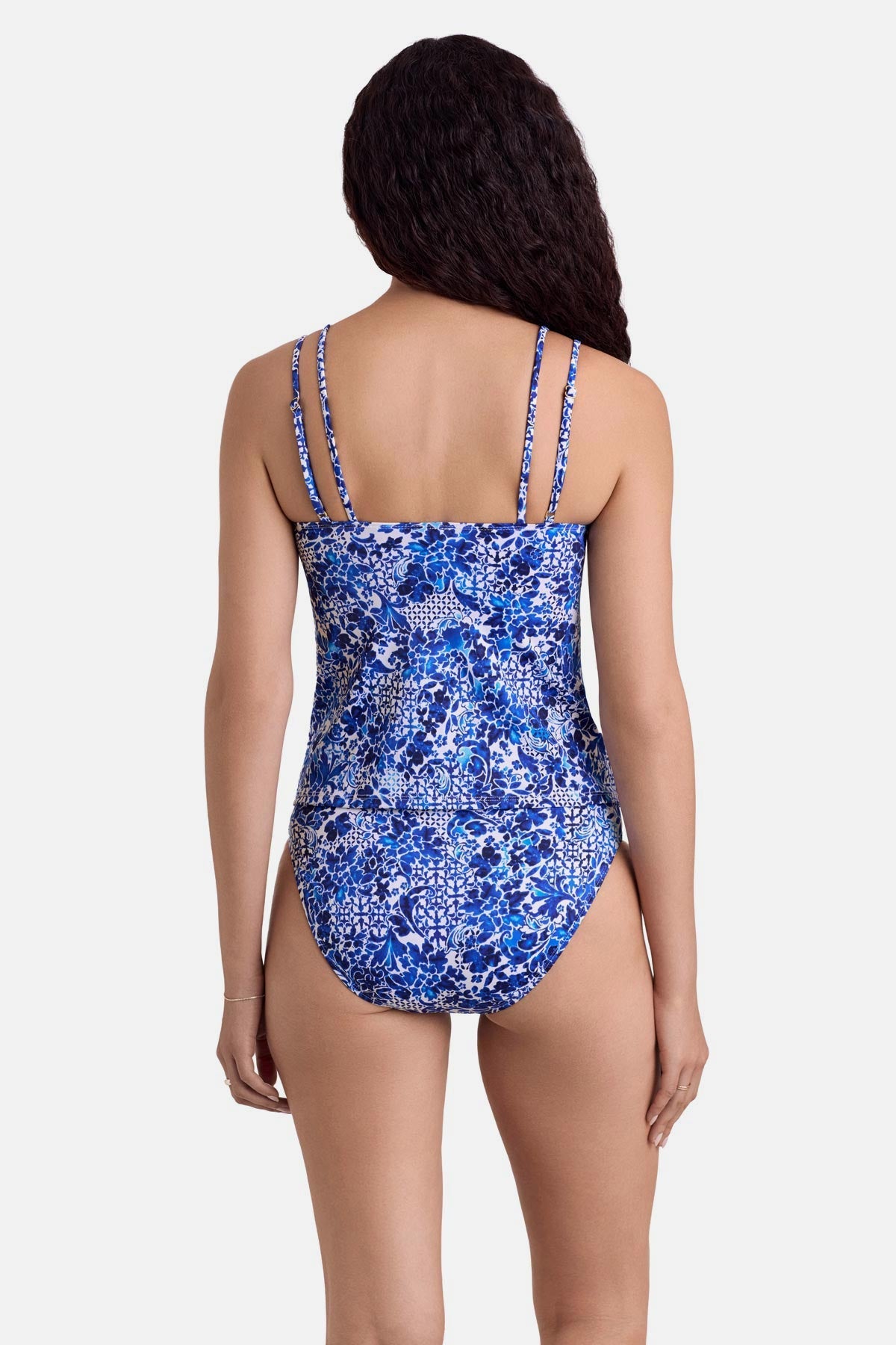 Woman turned away wearing a blue and white floral printed tankini top with matching swim bottoms